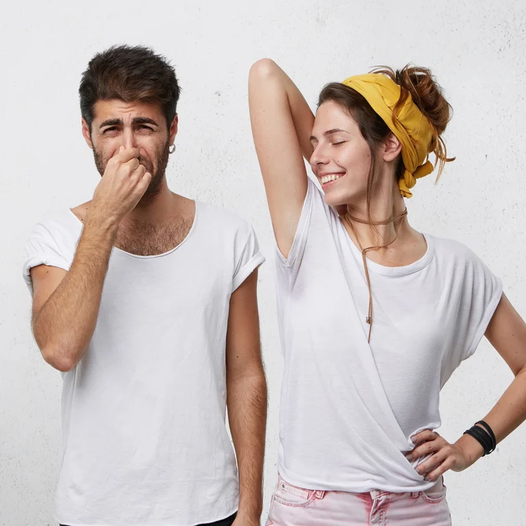 how-to-remove-armpit-odor - man holding nose woman holding up arm and smiling