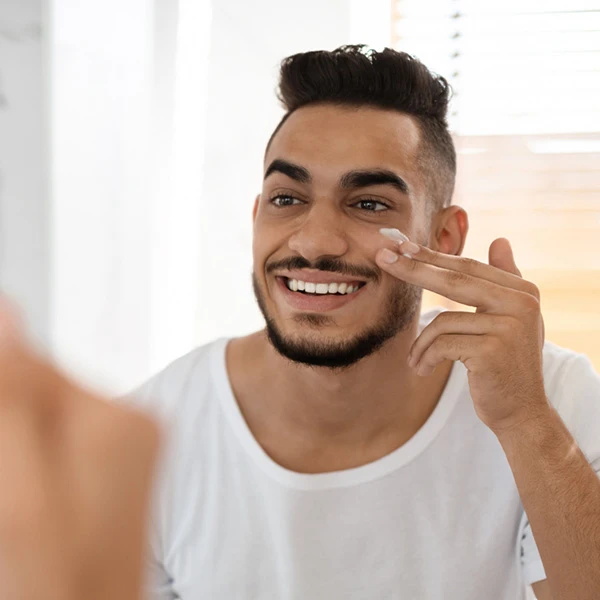 man putting cream on his face - skin care habits to start