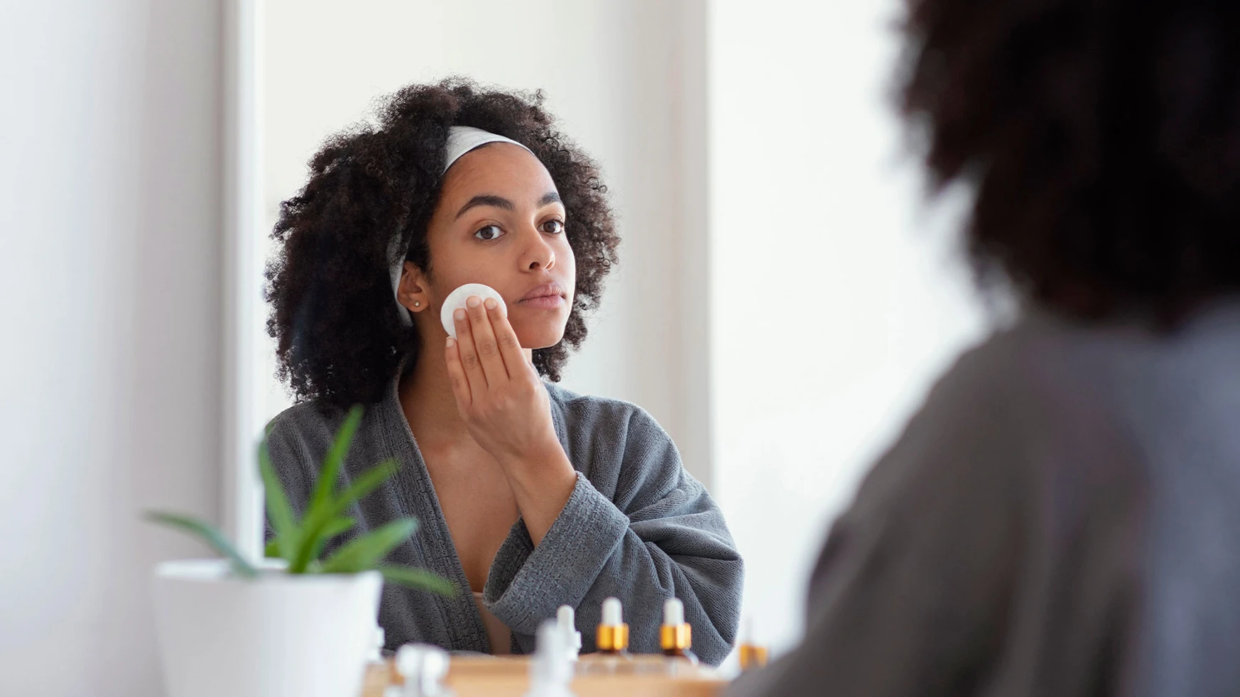 a woman cleaning her face with a cotton pad