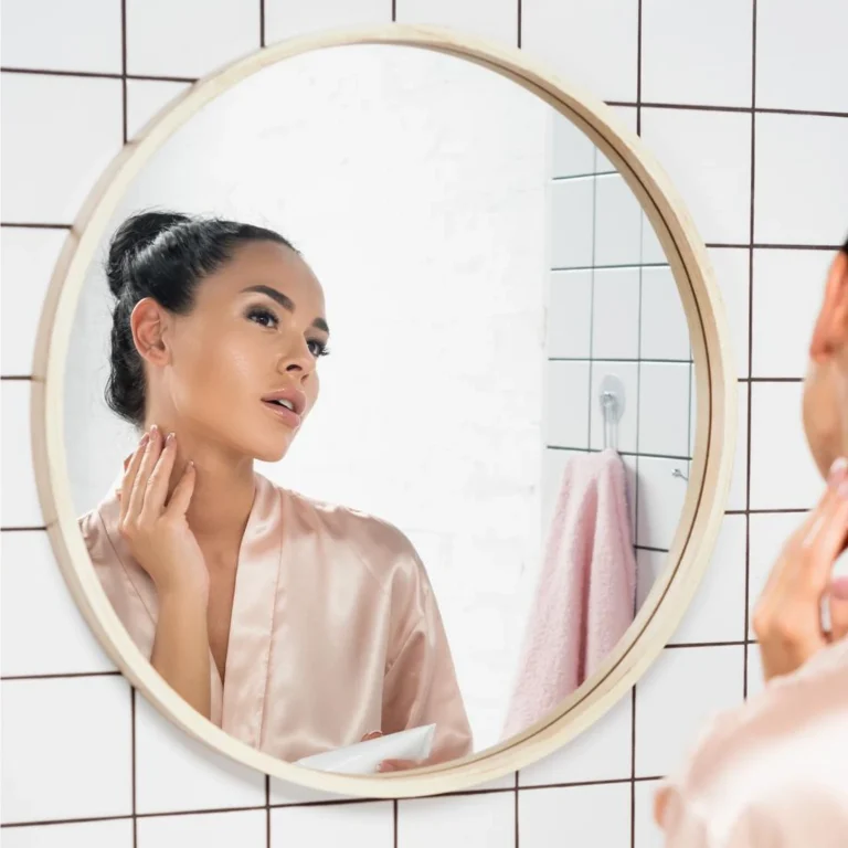 woman looking in the mirror touching her neck 1600x1600 px