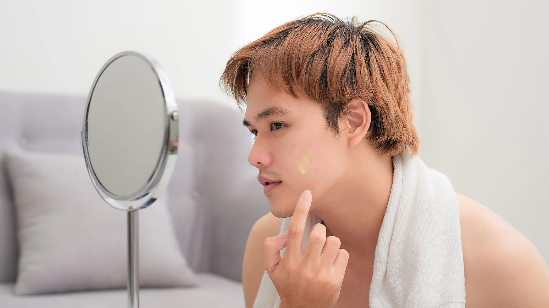 young-asian-man-applying-cream-to-face